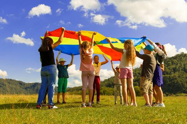 eine Gruppe Kinder steht im Kreis mit einem bunten Tuch